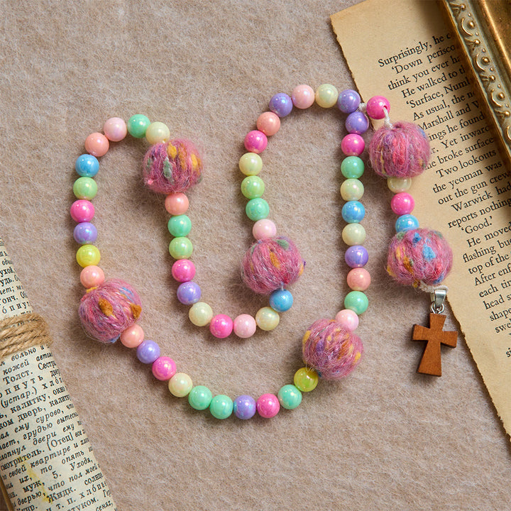 Christianartworkshop Rosario infantil de cuentas de macaron con pompones esponjosos y cruz de madera: emblema de la bondad celestial inocente. - Rosario esponjoso color macaron - image 0